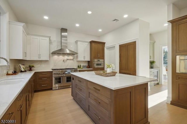 kitchen with visible vents, double oven range, white oven, wall chimney exhaust hood, and a sink