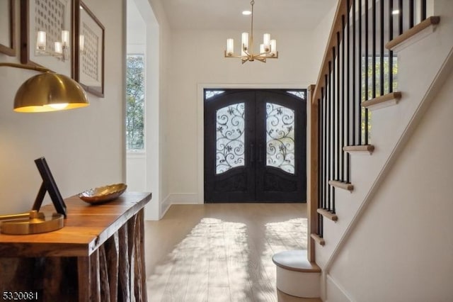 foyer entrance with an inviting chandelier, stairway, wood finished floors, and french doors