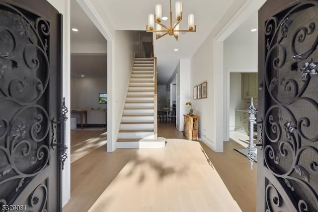 foyer featuring stairs, an inviting chandelier, recessed lighting, and wood finished floors