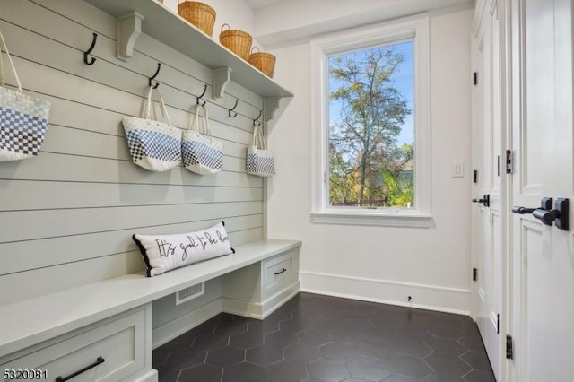 mudroom with baseboards and dark tile patterned flooring