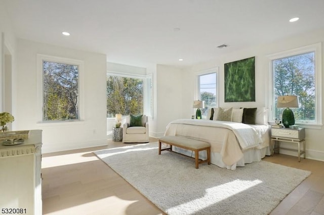 bedroom featuring multiple windows, wood finished floors, recessed lighting, and baseboards