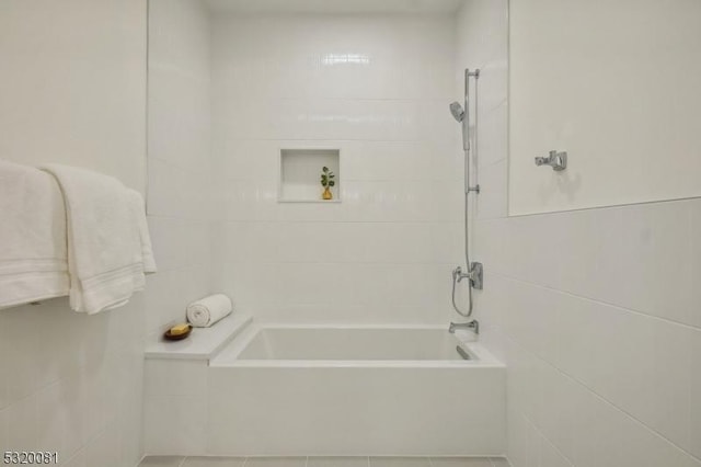 full bath with tile walls and shower / bathtub combination