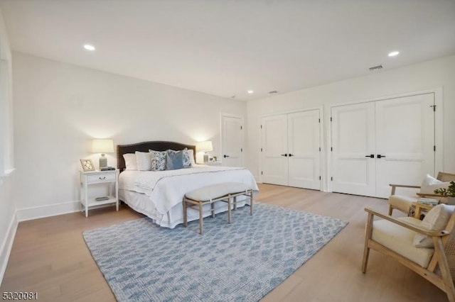 bedroom with visible vents, two closets, light wood-style flooring, recessed lighting, and baseboards