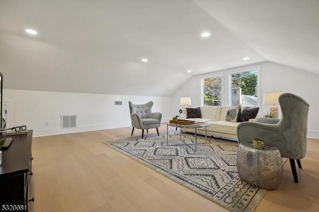 living area with visible vents, baseboards, lofted ceiling, and wood finished floors