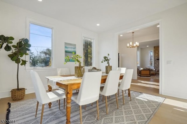 dining area with recessed lighting, baseboards, an inviting chandelier, and wood finished floors