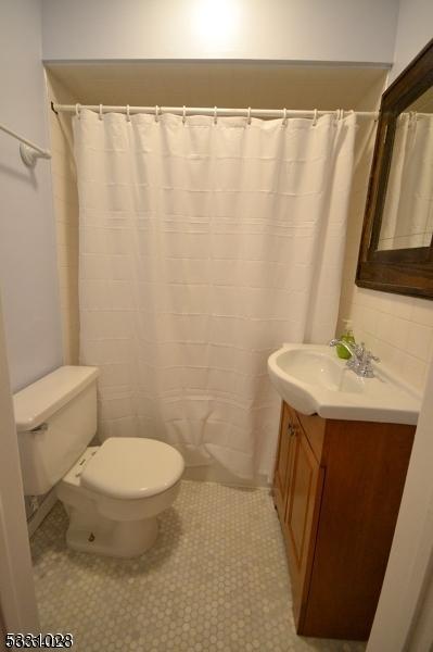 full bath featuring tile patterned flooring, a shower with shower curtain, toilet, and vanity