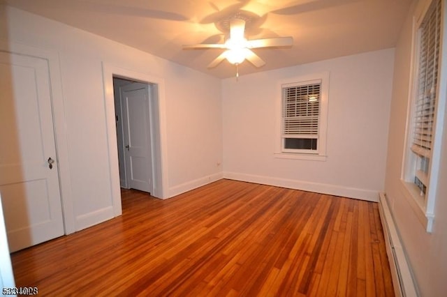 unfurnished bedroom with wood finished floors, baseboards, baseboard heating, and ceiling fan