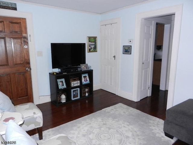 living room featuring crown molding, baseboards, and wood finished floors