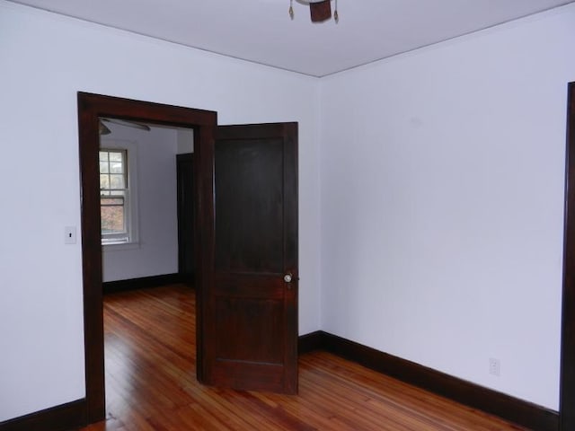 spare room with baseboards and wood finished floors