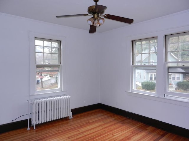 spare room with a wealth of natural light, light wood-style flooring, radiator heating unit, and baseboards