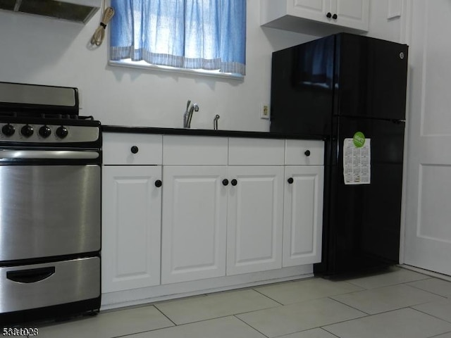 kitchen featuring freestanding refrigerator, extractor fan, white cabinets, dark countertops, and stainless steel gas stove