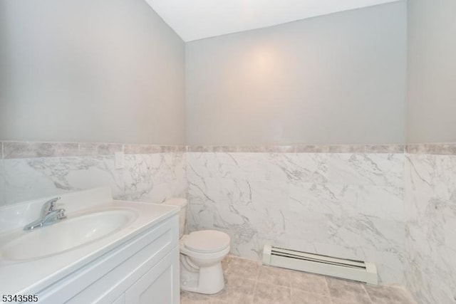 bathroom featuring toilet, tile walls, wainscoting, baseboard heating, and vanity