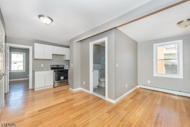 kitchen featuring light wood finished floors, gas stove, white cabinetry, and baseboards