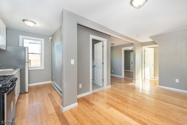 kitchen featuring a baseboard heating unit, gas range, baseboards, and light wood finished floors