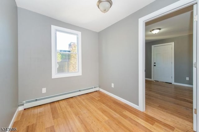 unfurnished room featuring baseboard heating, light wood-style flooring, and baseboards