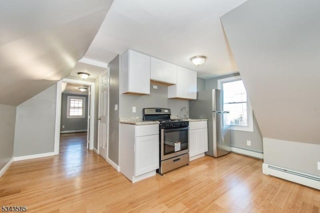 kitchen with a baseboard heating unit, light wood-style floors, white cabinets, stainless steel appliances, and a baseboard radiator