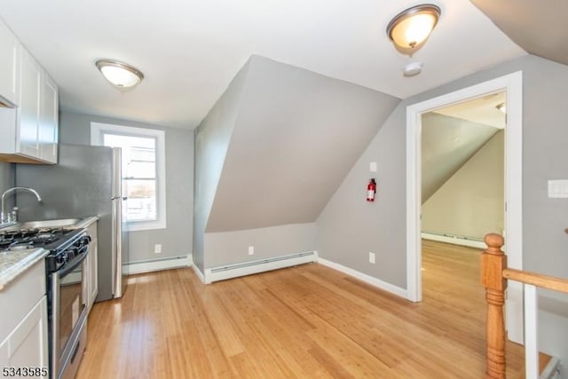 kitchen with stainless steel gas range oven, light wood-style floors, white cabinets, and a baseboard radiator