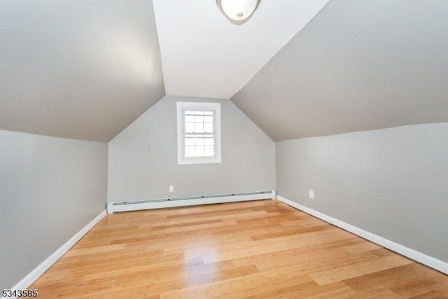 additional living space featuring wood finished floors, baseboards, and a baseboard radiator