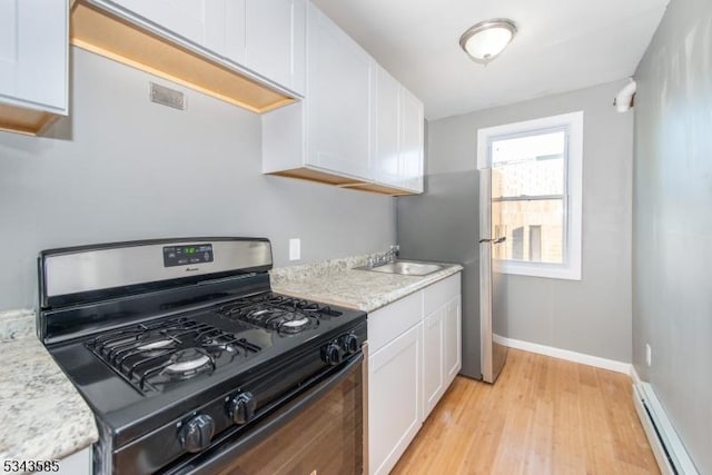 kitchen featuring range with gas stovetop, light wood-style flooring, baseboard heating, white cabinetry, and a sink