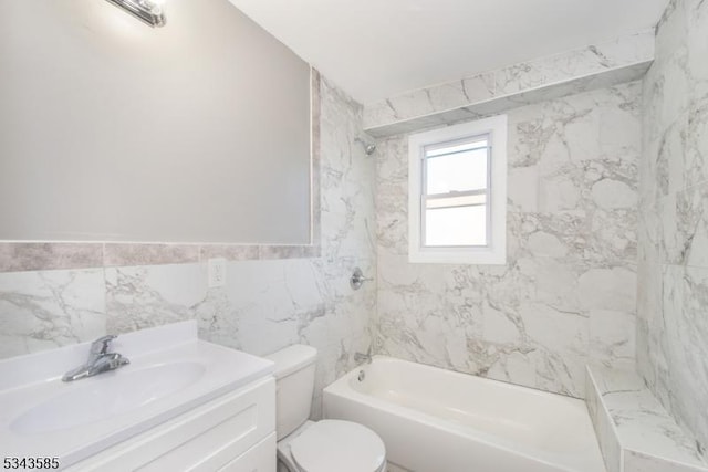 bathroom featuring toilet, vanity, tile walls, and shower / bathing tub combination