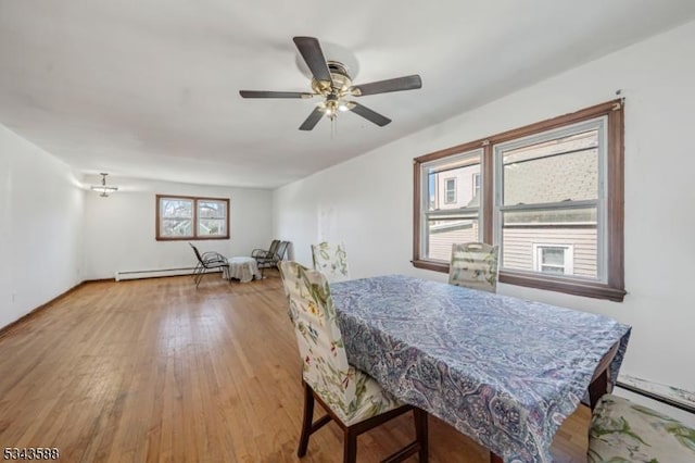 dining space featuring wood finished floors, baseboard heating, and ceiling fan