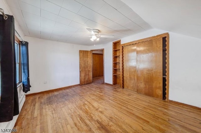 unfurnished bedroom featuring vaulted ceiling, a ceiling fan, baseboards, and wood finished floors