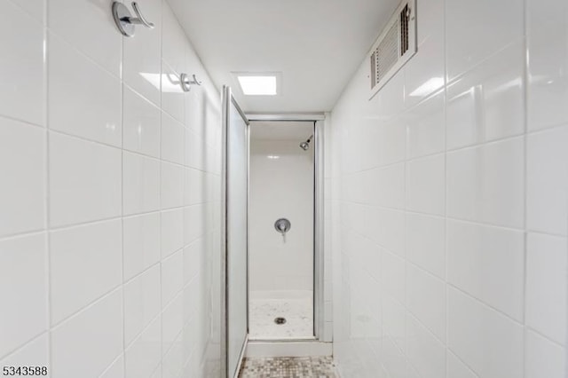 full bathroom with visible vents, tile walls, and a shower stall