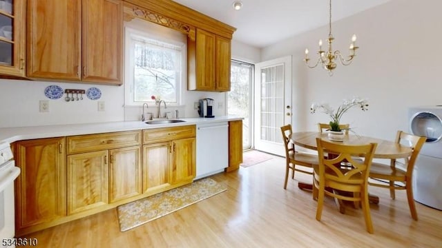 kitchen with a sink, light countertops, glass insert cabinets, dishwasher, and light wood-type flooring