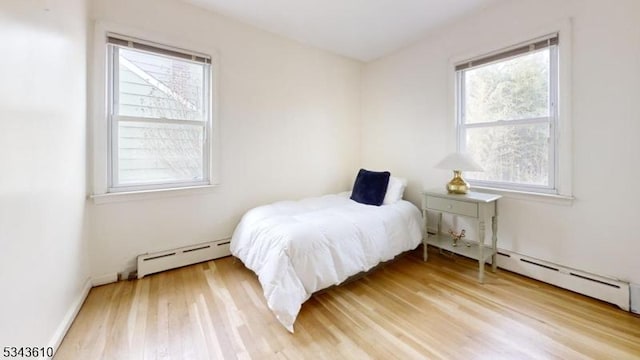 bedroom with light wood-style floors and baseboard heating