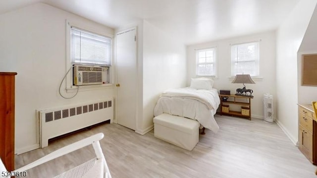 bedroom with radiator, baseboards, lofted ceiling, cooling unit, and light wood-style floors