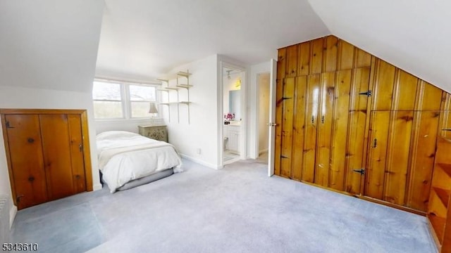 bedroom featuring ensuite bath, vaulted ceiling, baseboards, and carpet floors