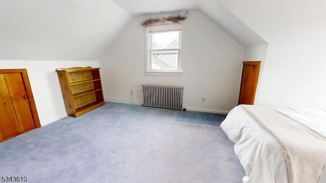 bedroom with lofted ceiling, radiator, and light carpet