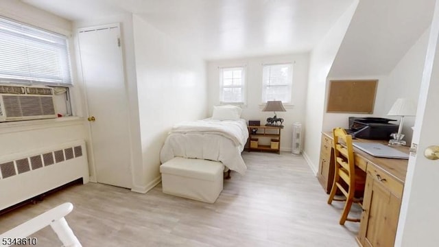 bedroom featuring cooling unit, baseboards, radiator, and light wood finished floors