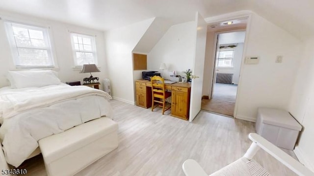 bedroom featuring lofted ceiling, radiator heating unit, baseboards, and light wood-type flooring