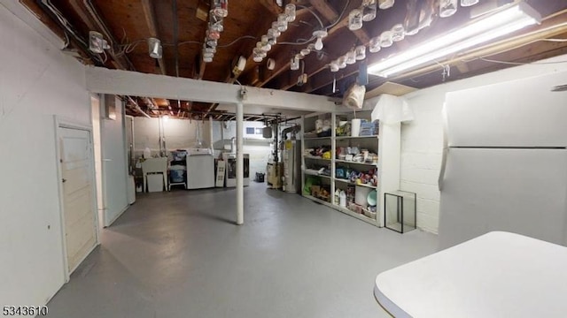 unfinished basement with independent washer and dryer, water heater, and freestanding refrigerator