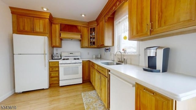 kitchen featuring premium range hood, white appliances, brown cabinetry, and a sink