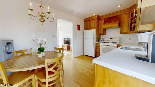 kitchen with premium range hood, light countertops, light wood-style flooring, white appliances, and a sink