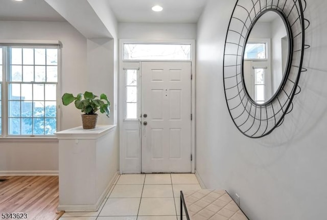 foyer entrance featuring visible vents, light tile patterned floors, a healthy amount of sunlight, and baseboards