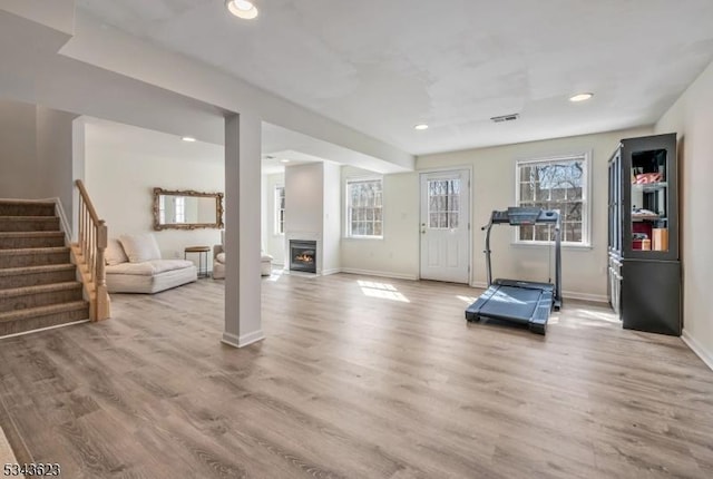 exercise room with visible vents, baseboards, a lit fireplace, recessed lighting, and wood finished floors