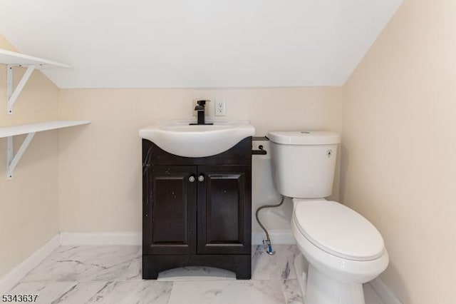 bathroom featuring toilet, lofted ceiling, marble finish floor, baseboards, and vanity