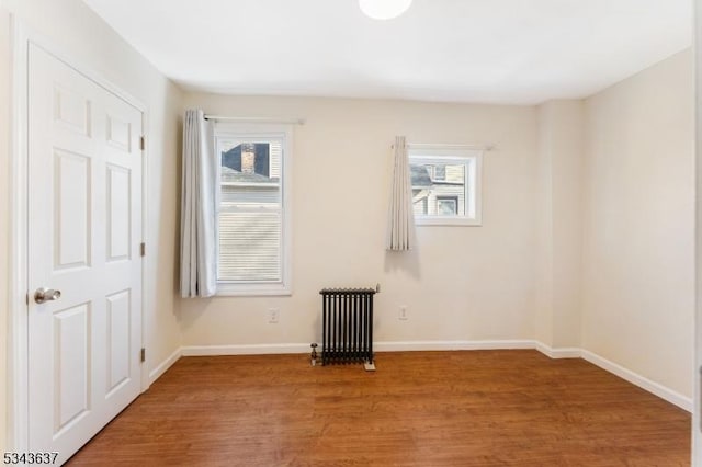 spare room with plenty of natural light, light wood-style flooring, radiator, and baseboards