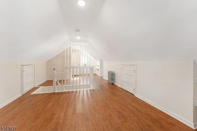 bonus room featuring lofted ceiling, radiator, wood finished floors, and baseboards