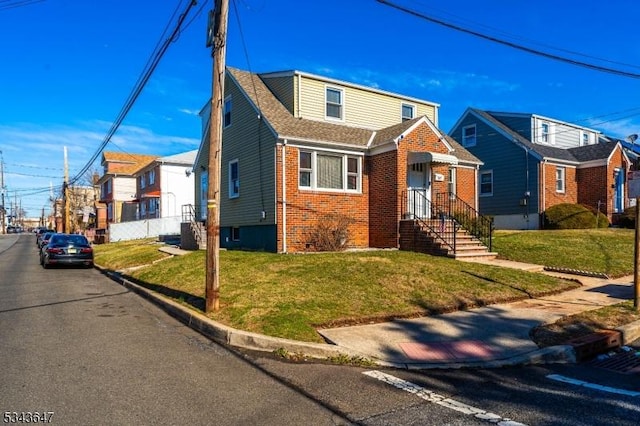 view of front facade featuring brick siding, a residential view, a front lawn, and roof with shingles