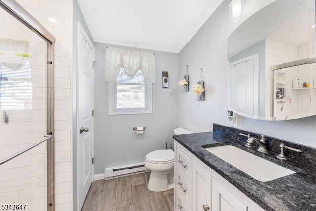 bathroom with a shower stall, a baseboard heating unit, toilet, wood finished floors, and vanity