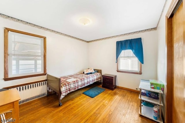 bedroom with radiator heating unit, baseboards, and wood-type flooring