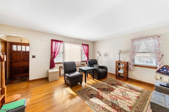 living room featuring arched walkways, baseboards, and wood finished floors