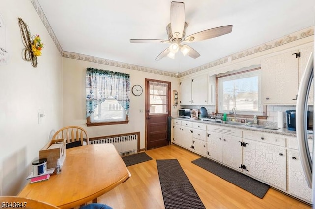 kitchen with light wood-style floors, light countertops, radiator heating unit, and stainless steel appliances