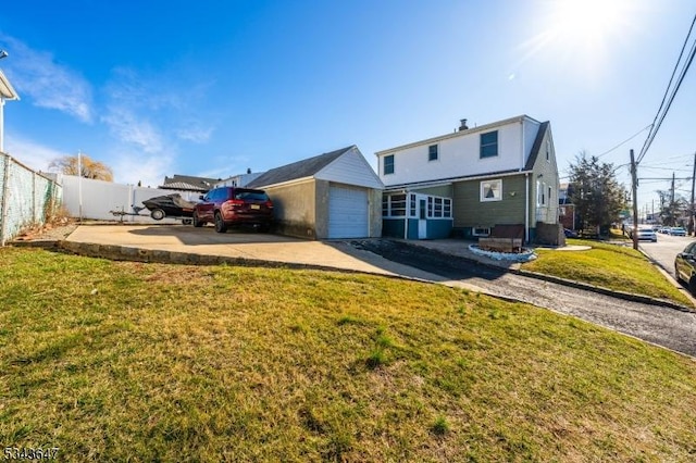 back of property with an attached garage, a lawn, fence, and driveway