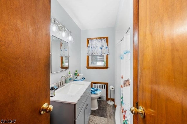 bathroom featuring vanity, a shower with shower curtain, radiator, wood finished floors, and toilet