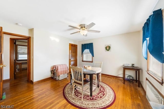 dining room with radiator heating unit, wood finished floors, baseboards, and ceiling fan